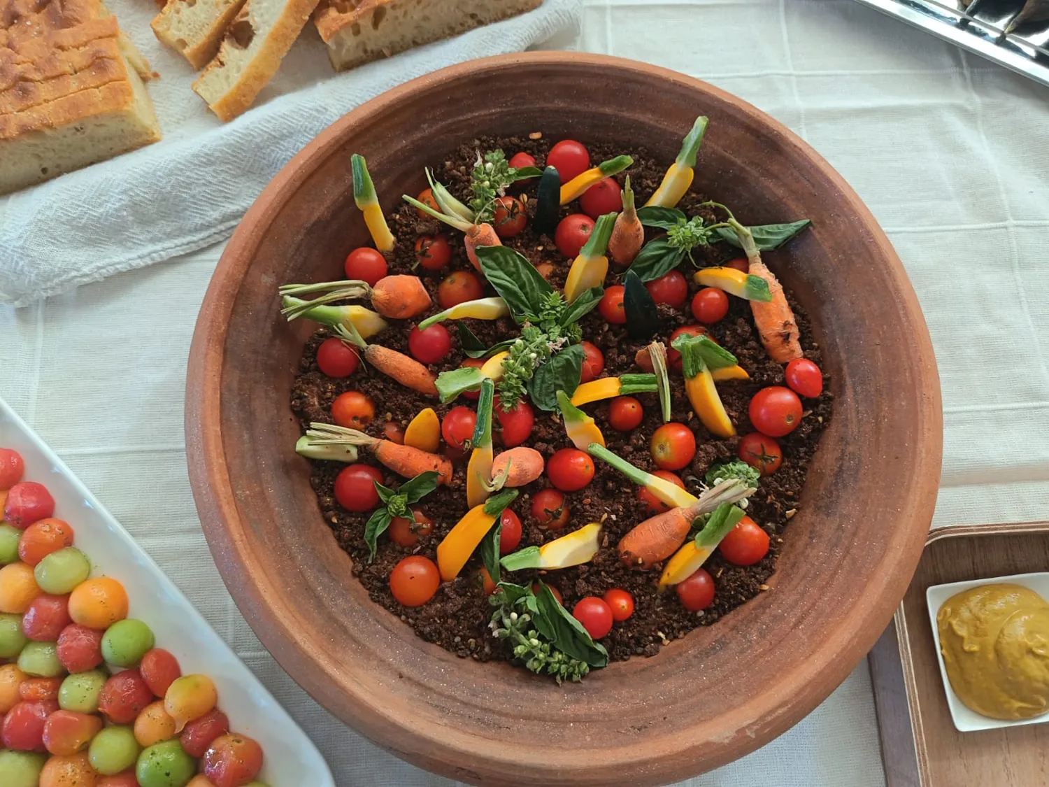Un bol en terre cuite de tomates et de petites carottes, avec des herbes