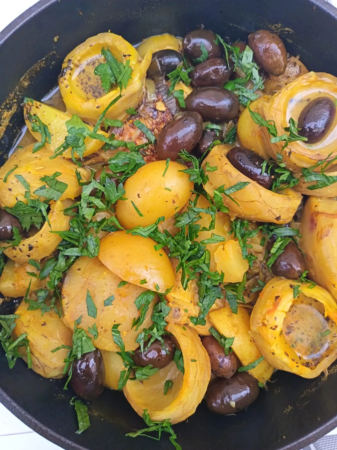 Fruits jaunes farcis, olives et herbes dans une poêle sombre